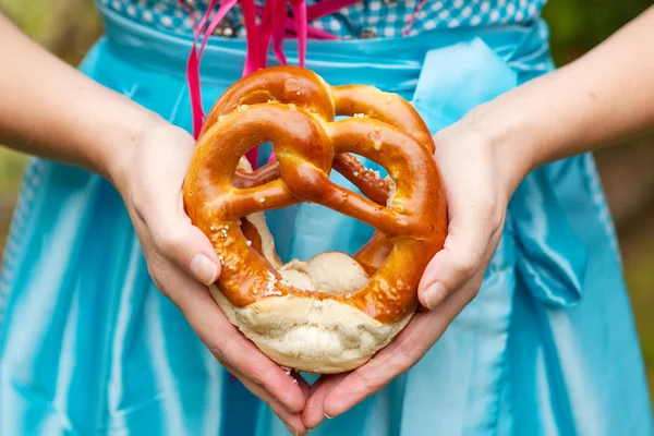 Happy beautiful woman in dirndl dress holding Oktoberfest  pretz — Stockfoto