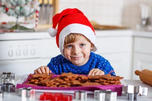 Little boy baking gingerbread cookies in domestic kitchen — Zdjęcie stockowe