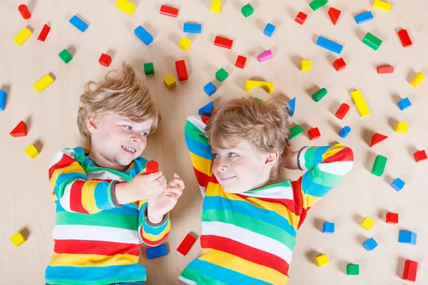 Dos niños pequeños jugando con bloques de madera de colores en interiores — Foto de Stock