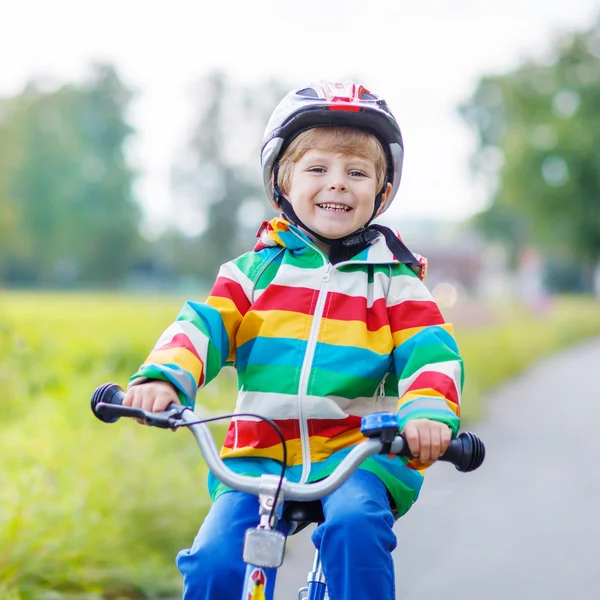 Garoto no capacete montando sua primeira bicicleta, ao ar livre — Fotografia de Stock