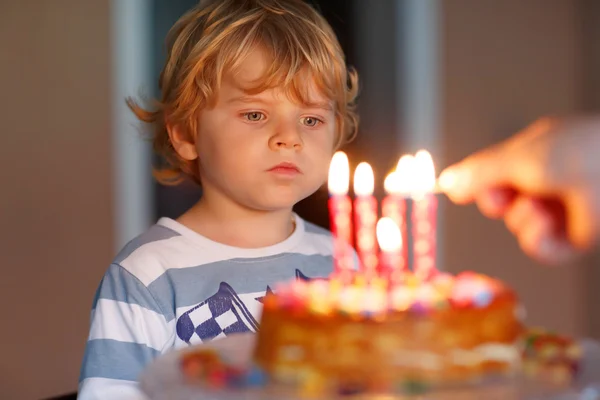 Kid jongen viert zijn verjaardag en blazen kaarsen op taart — Stockfoto