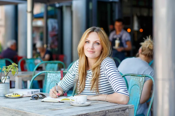 Femme buvant du café et écrivant des notes dans le café — Photo