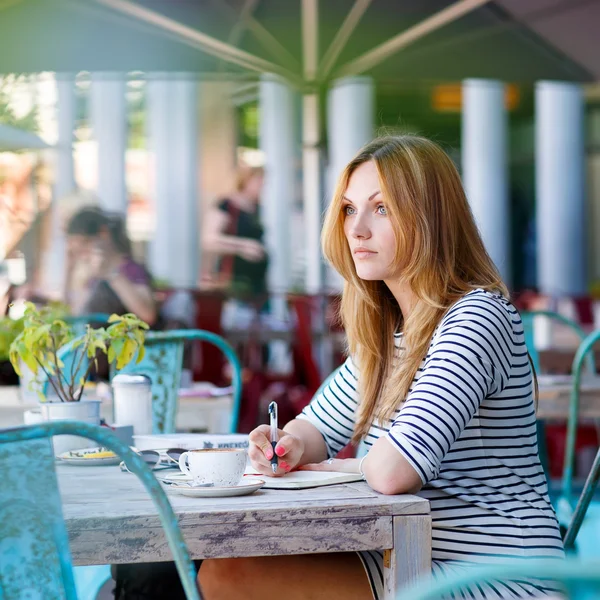 Mujer tomando café y escribiendo notas en la cafetería —  Fotos de Stock