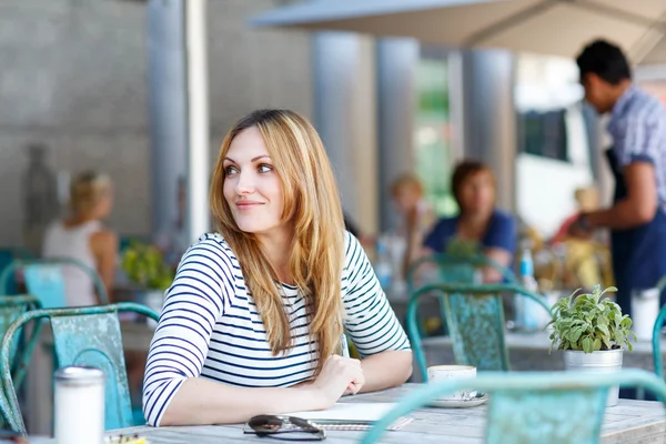 Žena, pití kávy a psaní poznámek v kavárně — Stock fotografie