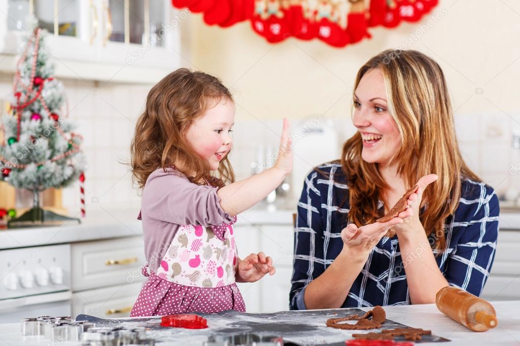 Mother and little kid girl baking gingerbread cookies for Christmas