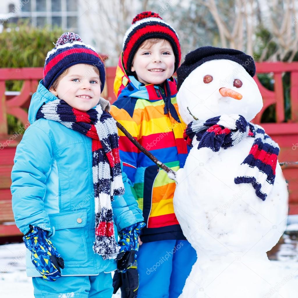 Two little siblings boys making a snowman, playing and having fu