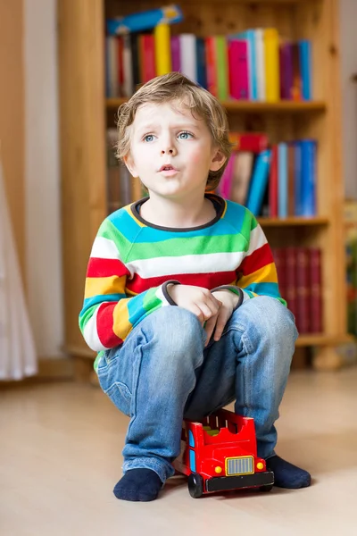 Kleiner blonder Junge spielt mit Holzspielzeugbus, drinnen — Stockfoto