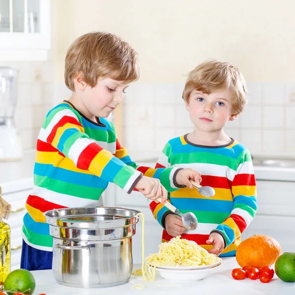 Dos niños comiendo espaguetis en la cocina doméstica . —  Fotos de Stock