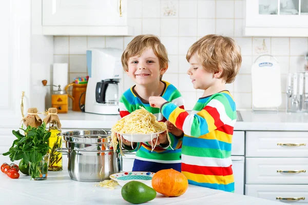 Two little kid boys eating spaghetti in domestic kitchen. — Stock Photo, Image