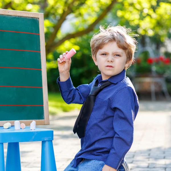 Menino no quadro negro aprendendo a escrever — Fotografia de Stock