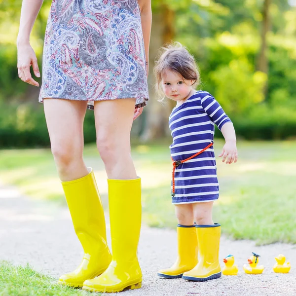 Mother and little adorable child in yellow rubber boots — Stock Photo, Image