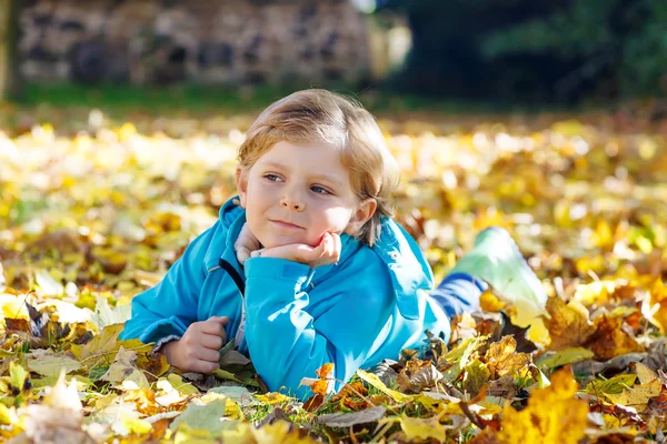 Little kid boy with yellow autumn leaves in park — Stock Photo, Image