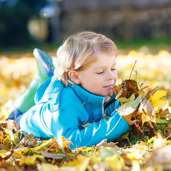 Kleiner Junge mit gelben Herbstblättern im Park — Stockfoto