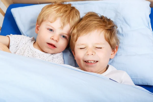 Små pojkar har roligt i sängen hemma — Stockfoto