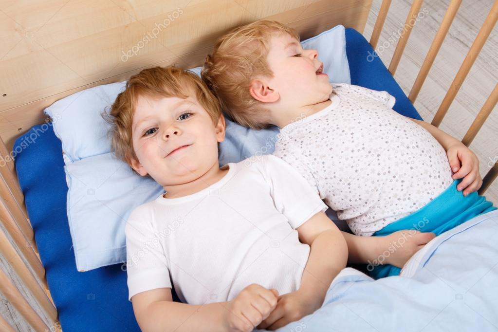 Two little toddler boys having fun in bed