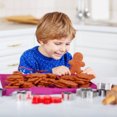 Little boy baking gingerbread cookies in domestic kitchen
