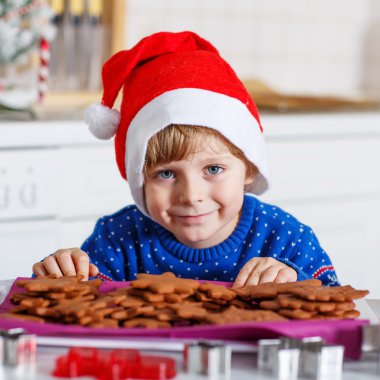 Little boy baking gingerbread cookies in domestic kitchen