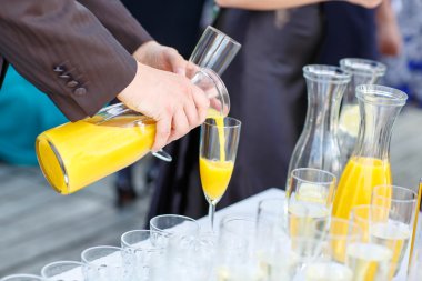 Hand of a man pouring orange juice on a wedding clipart