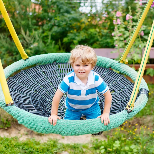 Roztomilé batole chlapce baví řetězce swing na venkovní playgroun — Stock fotografie