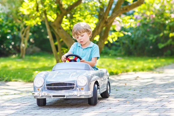 Petit garçon conduisant un gros jouet vieille voiture, à l'extérieur — Photo