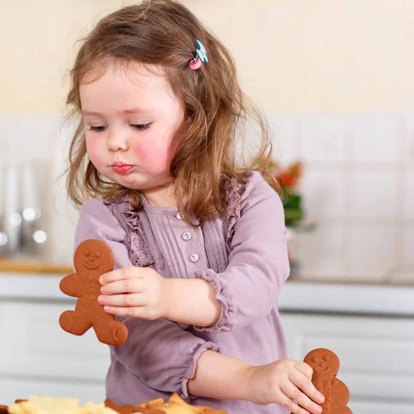 Kleines Mädchen backt Lebkuchen in der heimischen Küche — Stockfoto