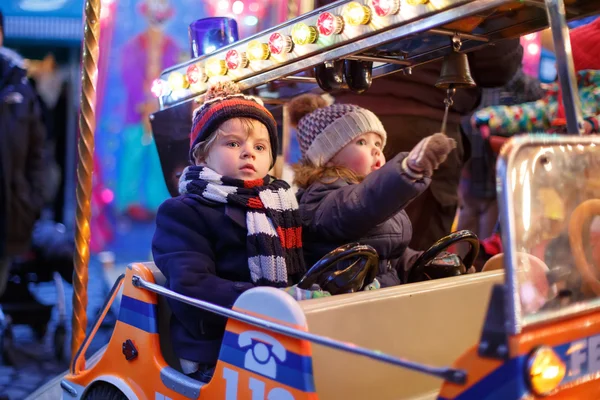 Menino e menina em um carrossel no mercado de Natal — Fotografia de Stock