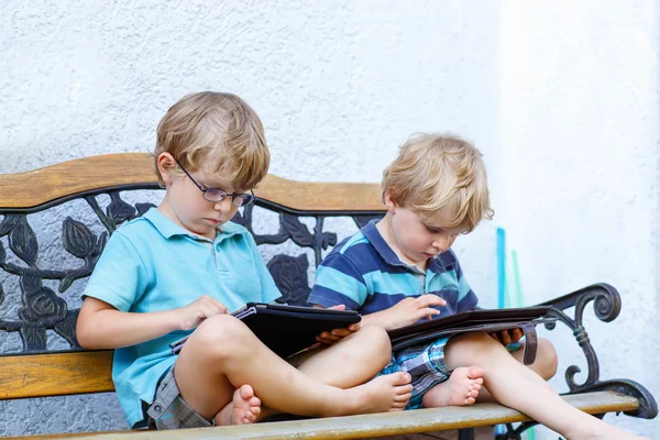 Two happy little boy friends holding tablet pc, outdoors. — Stok fotoğraf