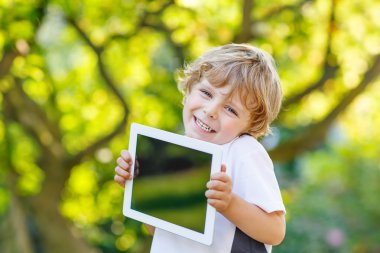 tablet pc, açık havada tutan gülümseyerek mutlu küçük çocuk