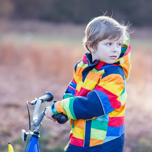 孩子安全头盔和 outd 多彩雨衣骑自行车的男孩 — 图库照片
