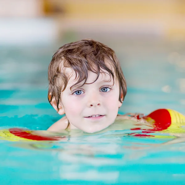 Mały chłopiec dziecko z swimmies uczyć się pływać w krytym basenem — Zdjęcie stockowe