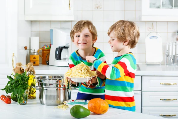 Два маленьких мальчика едят спагетти на домашней кухне . — стоковое фото