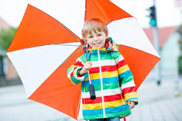 Pequeño niño rubio caminando con un gran paraguas al aire libre — Foto de Stock