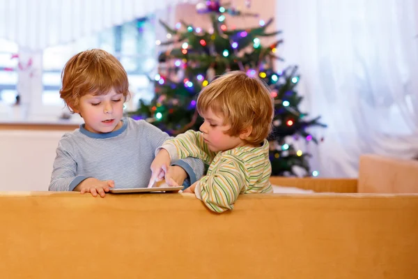 Two happy little kids playing with tablet pc, indoors — Stock Photo, Image