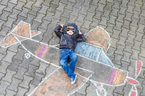 Little boy having fun with airplane picture drawing with chalk — Stock Photo, Image