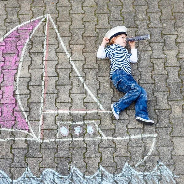 Niño pequeño que se divierte con el dibujo de la imagen del barco con tiza —  Fotos de Stock