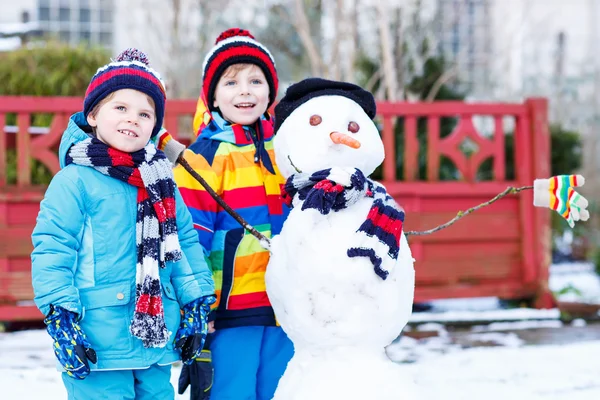 Two little friends making a snowman, playing and having fun with — Stock Photo, Image