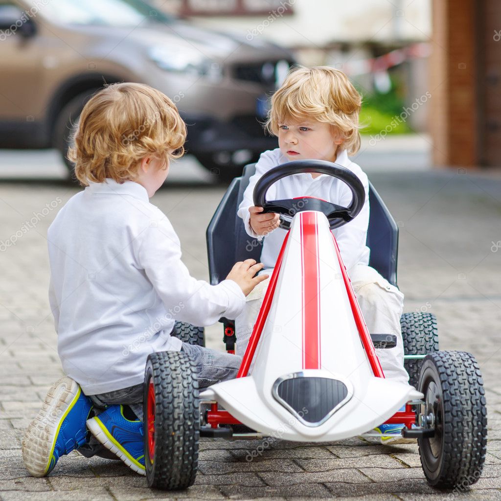Two happy sibling boys playing with toy car
