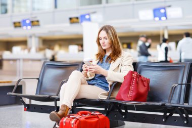 kadın uluslararası havaalanında uçuş terminalinde bekliyor