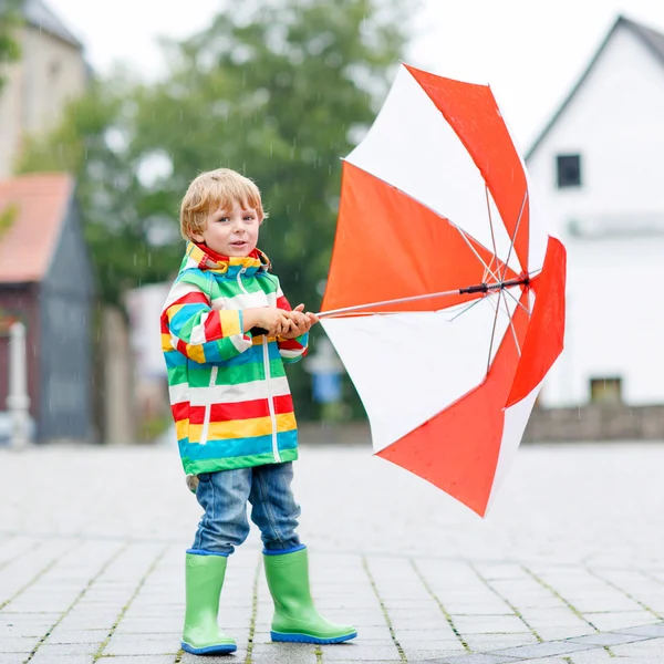 Piccolo ragazzo biondo che cammina con grande ombrello all'aperto — Foto Stock