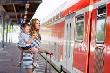 Sevimli küçük kız ve annesi bir tren istasyonu.