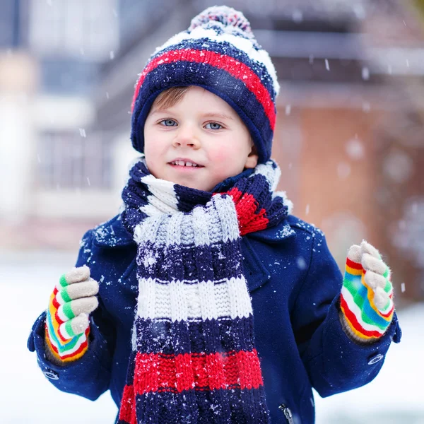 Söt liten rolig pojke i färgglada vinterkläder har roligt med — Stockfoto