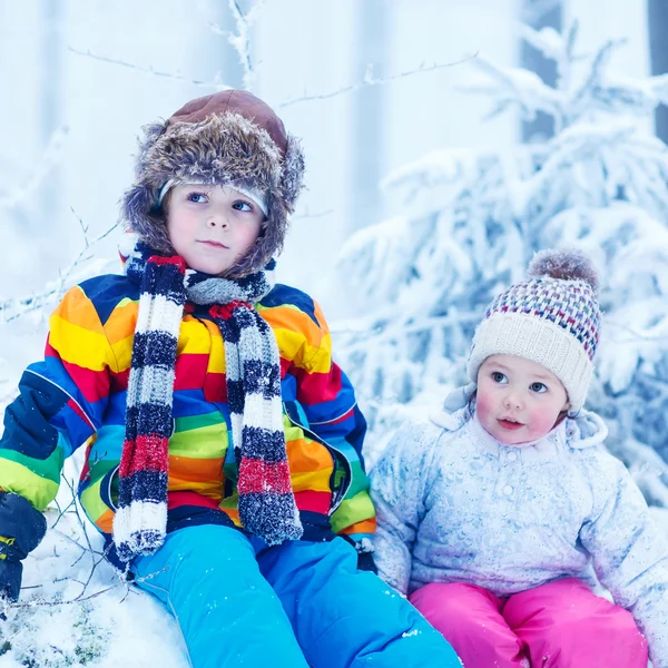 Porträtt av två barn: pojke och flicka i vinter mössa i snö skog — Stockfoto
