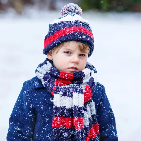 Schattige kleine grappige jongen in kleurrijke winterkleren met plezier met — Stockfoto