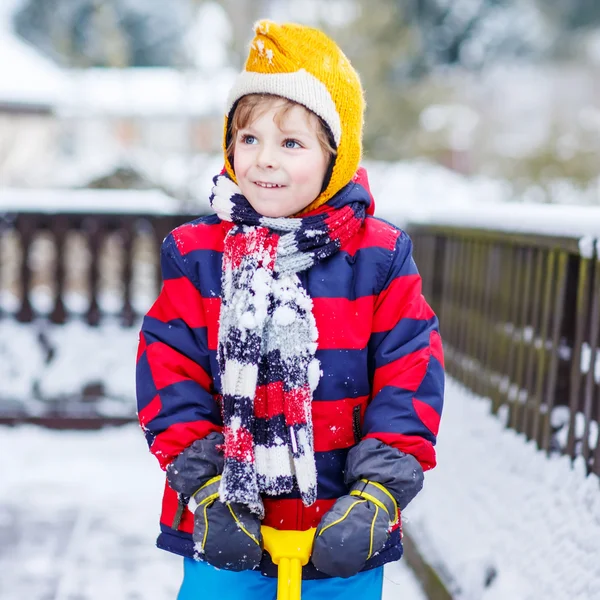 Смешной маленький мальчик в разноцветной одежде счастлив от снега, на открытом воздухе — стоковое фото