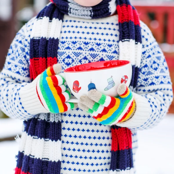 Manos de niño pequeño sosteniendo gran taza con copos de nieve y ch caliente —  Fotos de Stock