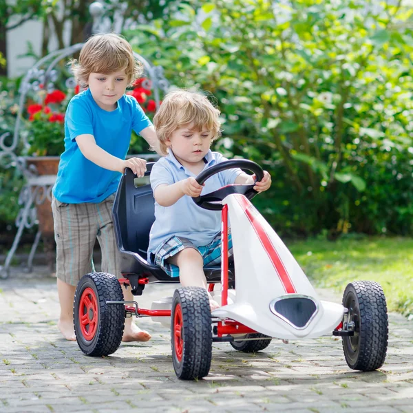 Dos niños felices que se divierten con el coche de juguete — Foto de Stock