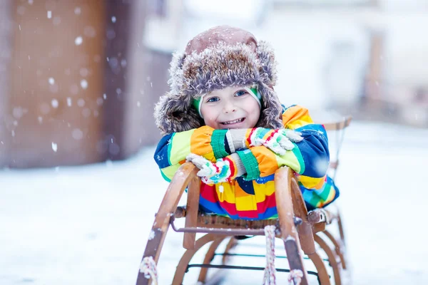 Schattige kleine grappige jongen in kleurrijke winterkleren met plezier met Stockfoto