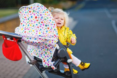Bebek arabasında oturan ve yürüyüşe çıkan küçük üzgün bir kızın portresi. Ağlayan bebek bebek bebek arabasında oturmak istemez. Sağlıklı bir kız. İki yıllık histerik kriz.