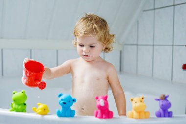 Çok sevimli şirin küçük yürümeye başlayan çocuk kız alma banyo küvet içinde. Kauçuk sakız oyuncaklar ile oynama ve eğlenerek mutlu sağlıklı bebek çocuk. Yıkama, temizlik, hijyen çocuklar için