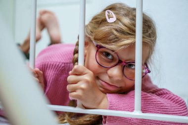 Evde gözlüklü, gülümseyen ilkokul çocuğunun samimi portresi..